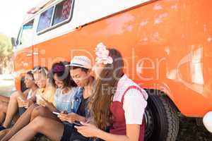 Friends using smart phone by camper van