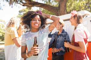 Portrait of woman holding beer bottle with friends in background