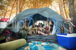 Happy young friends sitting together in tent
