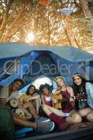 Portrait of happy friends enjoying while sitting in tent