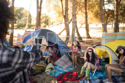 Man photographing smiling friends through mobile phone