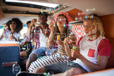 Young friends blowing bubble wands in camper van