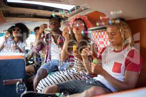 Young friends blowing bubble wands in camper van
