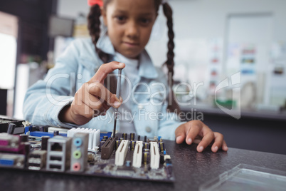Elementary girl assembling circuit board at electronics lab