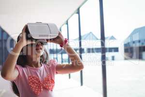 Schoolgirl using virtual reality glasses in corridor