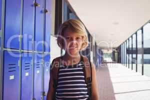 Portrait of smiling boy standing by lockers in corridor