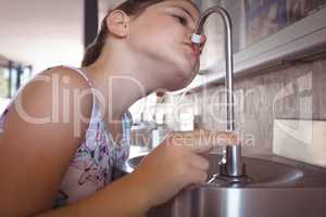 Girl drinking water from faucet