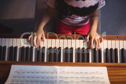 Overhead view of girl practicing piano in classroom