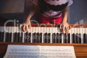 Overhead view of girl practicing piano in classroom