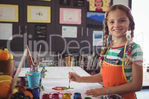 Portrait of smiling girl painting at desk