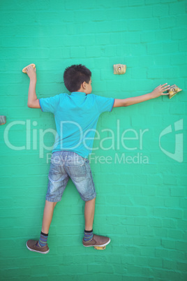 Rear view of boy climbing on green wall
