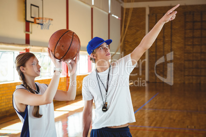 Male coach advising female basketball player