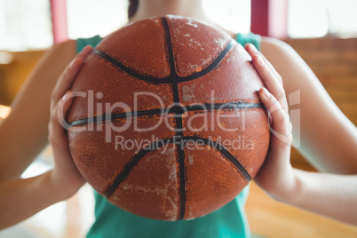Midsection of female basketball player holding ball