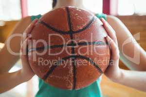 Midsection of female basketball player holding ball