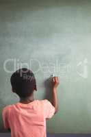 Boy writing with chalk on greenboard