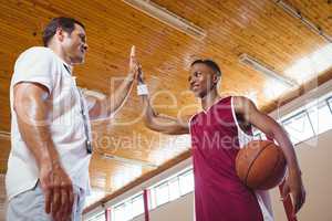 Low angle view of basketball player high fiving with coach