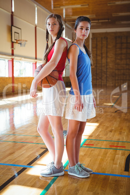 Portrait of female basketball players standing back to back