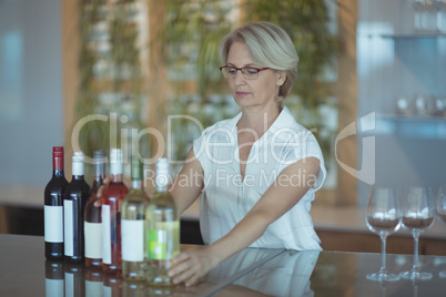 Businesswoman arranging winebottles on table