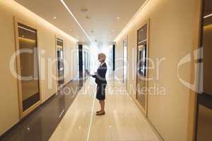 Businesswoman using laptop in corridor