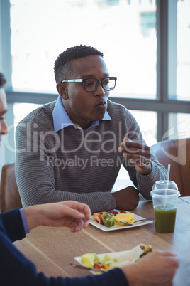 Male business colleagues having breakfast at office cafeteria