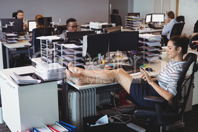 Young businesswoman relaxing while colleagues working in office