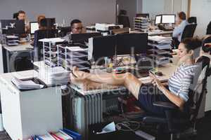 Young businesswoman relaxing while colleagues working in office