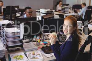 Portrait of businesswoman having snack while colleagues working in creative office