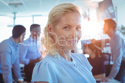 Portrait of smiling businesswoman with team in background