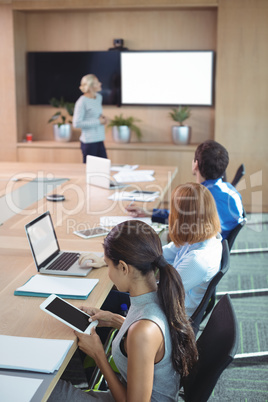 High angle view of businesswoman using digital tablet while sitting during meeting