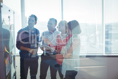Happy business entrepreneurs looking at whiteboard seen through glass