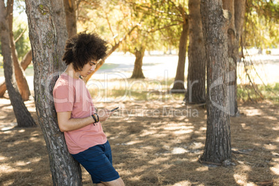 Side view of man using mobile phone at forest