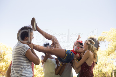 Playful friends carrying cheerful woman