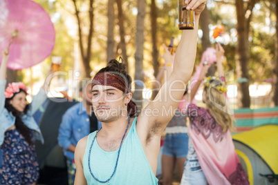 Young man holding beer bottle at campsite