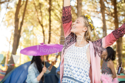 Happy woman with eyes closed raising hands at campsite