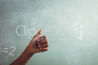 Cropped hand of student showing thumb against blackboard