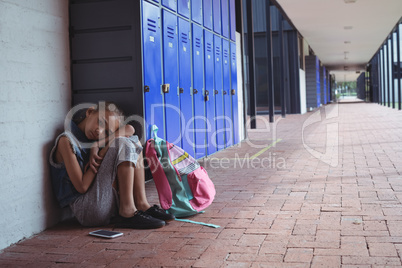 Full length of elementary schoolgirl resting by lockers