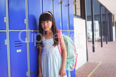 Portrait of elementary schoolgirl standing by lockers
