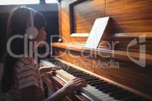 Girl looking at digital tablet while practicing piano in classroom
