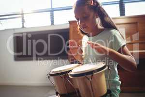 Girl playing bongo drums in classroom
