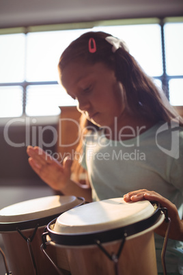 Girl practicing bongo drums in classroom