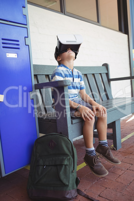 Boy using virtual reality glasses while sitting on bench