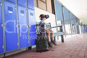 Full length of boy using virtual reality glasses while sitting on bench