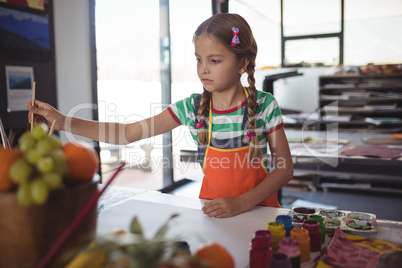 Girl painting at desk in classroom