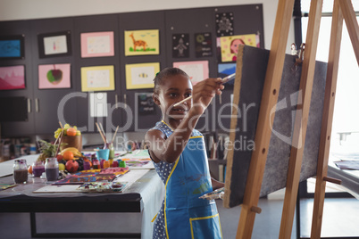 Confident girl painting on canvas