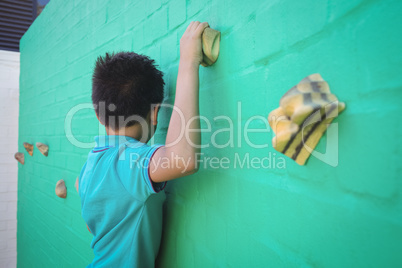Side view of boy climbing wall