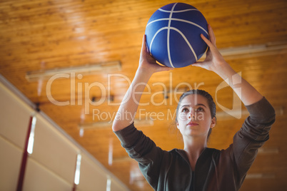 Woman practicing basketball in court