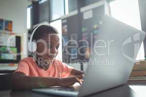 Boy listening music while using laptop