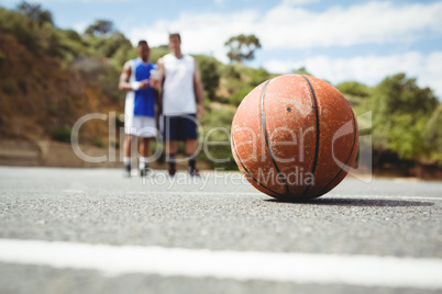 Orange basketball on ground with player standing in background