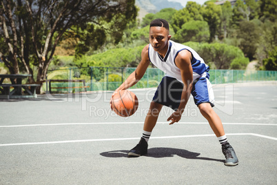 Full length of teenage boy practicing basketball