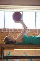 Female player playing with basketball while lying on bench in court